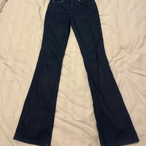Mörkblå bootcut jeans från Zara - Snygga mörkblå jeans från Zara i bootcut-modell. Klassisk femficksdesign med silverfärgade nitar och normal passform. Jeansen är tillverkade i ett mjukt denimtyg som sitter skönt och ger en stilren look. Jag skulle säga att jeansen är mittemellan low och medel i midjan. Jag är 168cm som referens 