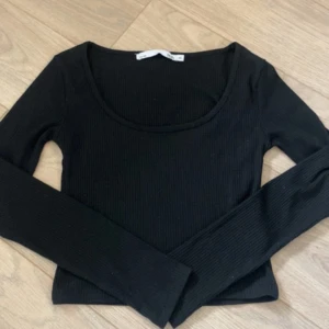 Svart ribbad långärmad topp - Säljer en svart ribbad långärmad topp från Bik Bok. Modellen är croppad med rundad halsringning och har en slim passform som sitter snyggt på kroppen. Perfekt att styla med jeans eller kjol för en clean look.