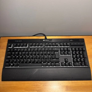 Mekaniskt tangentbord Corsair Strafe RGB MK.2 - Corsair Strafe RGB MK.2 är ett mekaniskt gamingtangentbord med Cherry MX Red-switchar, dynamisk RGB-belysning kompatibel med iCUE för egna ljusprofiler och dedikerade mediaknappar. Tangentbordet är i mycket gott skick och levereras med originalkartong + Handledsstöd. Perfekt för gaming och  vardaglig användning. 