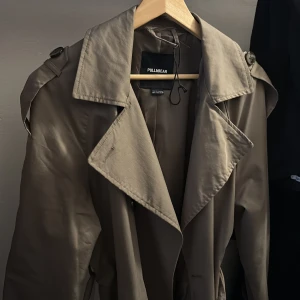 Beige trenchcoat från Pull&Bear - Används inte längre lite sönder de uppe vid hängaren ni kan se på bild 2. Annars är den fortfarande i nyskick 