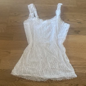 Vit spetsig linnetopp med smala axelband - Säljer ett jätte fint vitt linne i spets med smala axelband. Perfekt  till lager på lager outfits för en extra detalj! Köpt på Vinted och märket eller storleken står tyvärr inte men sitter som en xs/s!