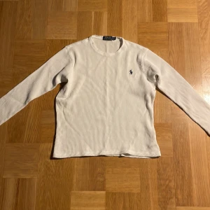 Vit ribbad tröja från Polo Ralph Lauren - Snygg vit långärmad tröja från Polo Ralph Lauren i ribbad bomull. Klassisk design med rund hals och diskret broderad logga på bröstet. Perfekt för dig som gillar stilrena och tidlösa plagg med en sportig touch. M barnstorlek, uppskattning xxs ”vanlig” storlek.