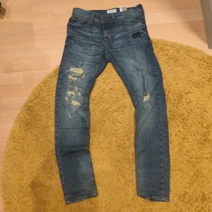 Blå slim jeans med slitningar - Snygga blå jeans från Only & Sons med skinny passform och slitna detaljer på både fram och baksida. Klassisk femficksmodell med normal midja och dragkedjegylf. 
