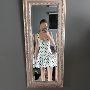 Vit prickig kortklänning med volang - Supersöt vit kortklänning med svarta prickar.