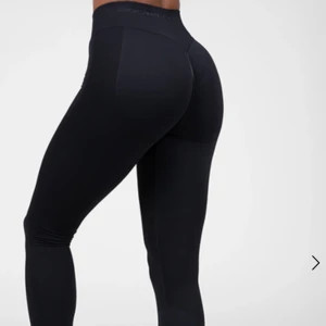 Svarta leggings från Gorilla Wear - Snygga svarta leggings från Gorilla Wear med hög midja och tight passform. De har diskreta meshdetaljer längs benen och en liten logga framtill. Perfekta för träning eller gymmet, tillverkade i ett stretchigt syntetmaterial som sitter skönt på kroppen.