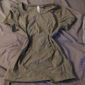 Olivgrön t-shirt  - En enkel olivgrön t-shirt med rund hals och korta ärmar. T-shirten är gjord i mjuk bomull och har en klassisk passform som funkar till många olika stilar. Perfekt för dig som gillar basic och neutrala färger.