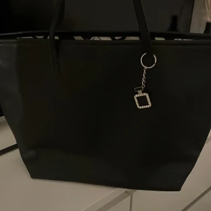 Svart axelväska med parfymcharm - Svart axelväska som är stor till förvaring med snygga parfymflaskor inuti, använd fåtal gånger och inga defekter 