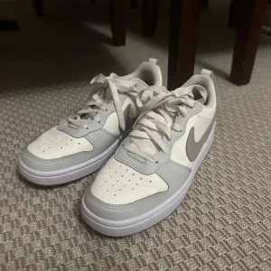 Nike Court Borough - Snygga Nike sneakers i vit och ljusgrå färg med snörning. Använda 1 gång. Finns även paketpris vid köp av skorna i andra annonsen :)