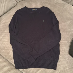 Ralph Lauren Stickad sweatshirt - Säljer en mörkblå stickad tröja från Polo Ralph Lauren i storklek M, använt den några gånger men den är fortfarande i bra skick, inga defekter. Nypris: 2100kr 