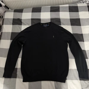 Svart tröja från Polo Ralph Lauren - Svart långärmad tröja från Polo Ralph Lauren med klassisk rund hals och broderad logga på bröstet. Slim fit och tillverkad i mjuk bomull som känns skön mot huden. Perfekt för dig som gillar stilrena och enkla plagg med en touch av premium. Priset går att diskutera 