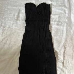 Svart ribbad långklänning Gina Tricot - Supersnygg svart långklänning från Gina Tricot. Den har en slit och kommer ner till vaderna.