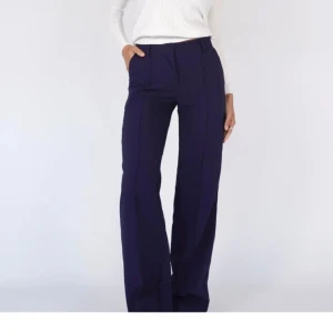 Mörkblå snygga kostymbyxor - Snygga mörkblå kostymbyxor med medelhög midja och vida ben. Org pris 780kr.💙Byxorna har klassisk passform, pressveck och hällor för bälte. Perfekta för en clean och stilren look. Materialet känns mjukt och följsamt. Endast använda en gång.💙