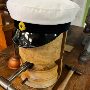 Studentmössa upssala modellen blå st 52-53 - Klassisk studentmössa från CTH med vit ovandel i bomull, mörkblå band och blank svart skärm. Framtill sitter en gul och blå kokard. Insidan har ett foder i gult och blått satin. Perfekt för studenten och svensk tradition. Mössan har ett blått band