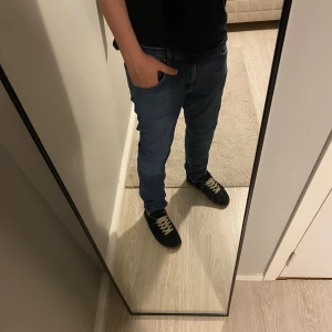 Blå Rider jeans W31 L30 - Snygga blå Rider jeans i klassisk modell med fem fickor och kontrastsömmar. Jeansen har en rak passform och normal midja, tillverkade i slitstarkt bomullsmaterial. Perfekta för dig som gillar en enkel och stilren look.