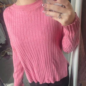 Rosa ribbad stickad tröja från Zara - Superfin rosa stickad tröja från Zara med ribbat mönster och rund halsringning. Långärmad och i mjukt material som känns skönt mot huden. Perfekt att styla med jeans eller kjol för en chill look.