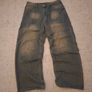 Wide jeans från Manfinity - Säljer ett par blå wide jeans från Manfinity i storlek L. Modellen har breda ben och klassisk femficksdesign med dragkedja och knapp framtil samt vita fläckar på fram och baksidan som ger en unik look. Jeansen är tillverkade i jeansmaterial och har en avslappnad passform. Pris kan diskuteras!