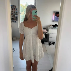 Vit kort klänning med puffärm - Säljer en söt vit kort klänning med puffärmar och broderade detaljer. Klänningen har v-ringad hals, volangkant nedtill och är tillverkad i ett lätt bomullstyg. Perfekt för sommarens alla tillfällen, superfin passform och romantisk stil.