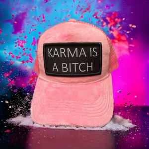 Rosa keps med textplatta - Snygg rosa keps i mjukt material med stor svart textplatta framtill där det står 'KARMA IS A BITCH' i vita bokstäver. Kepsen har klassisk form med böjd skärm och mesh på sidorna. Perfekt statement piece för dig som vill sticka ut.