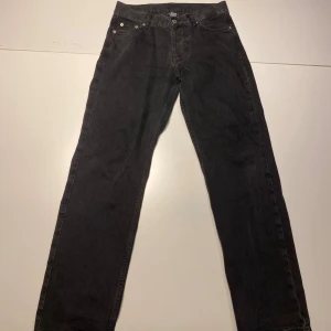 Svarta raka jeans från sweet SKTBS - Snygga svarta jeans från sweet SKTBS med klassisk femficksdesign och raka ben. Jeansen har en mörk tvätt och är tillverkade i slitstarkt bomullstyg. Perfekta för dig som gillar en enkel och stilren look.