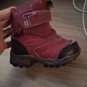 Rosa vinterkängor från Nordbjørn - Säljer ett par rosa vinterkängor från Nordbjørn med grov sula för extra grepp. Kängorna har kardborreband för enkel på- och avtagning, förstärkt tå och vadderad insida för värme. Materialet är slitstark syntet med detaljer i skinn och textil. Perfekt för kalla dagar!