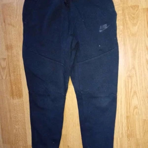 Svarta mjukisbyxor från Nike - Svarta mjukisbyxor från Nike med logga på benet. Byxorna har en slim passform, hög midja och dragkedja på fickan. Tillverkade i mjukt bomullsmaterial, perfekta för chill eller träning. Snyggt och stilrent snitt som passar till sneakers.