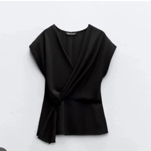 Svart omlottopp med knyt från Zara - Säljer en svart omlottopp från Zara med snygg knytning i midjan och v-ringad hals. Storlek S!!!