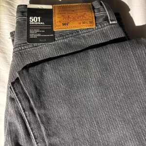 Levi's 501 grå jeans - Säljer ett par helt nya Levi's 501 jeans grått med randigt mönster då de var för små. 
