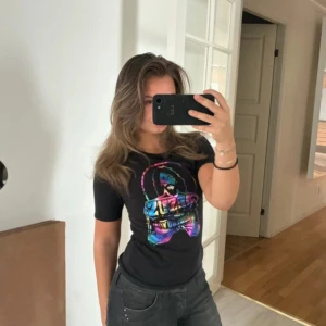 Svart Jesus is my Homeboy t-shirt Spank - Svart t-shirt från Spank med färgstark tryckt grafik på bröstet där det står 'Jesus is my Homeboy'. T-shirten har rund hals, korta ärmar och en figurnära passform. Materialet är mjuk bomull och trycket har en regnbågsfärgad vibe.