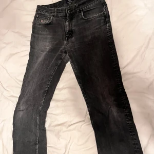 Svarta jeans från GANT - Snygga svarta jeans från GANT med slitna detaljer och klassisk femficksdesign. Jeansen har en rak passform och är tillverkade i mjukt denimtyg med lite stretch för extra komfort. Perfekta för dig som gillar en stilren och avslappnad look.