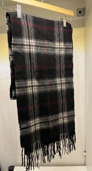 Ullhalsduk från A.Christensen - Rutrandig ullhalsduk med mörka färger som passar perfekt att ha under vintern. 100% ull   Skriv vid minsta fundering !
