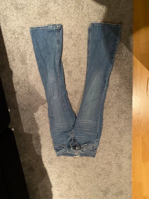Blå bootcut jeans från Perfect Jeans - Snygga blå jeans från Gina i modell Perfect Jeans i storlek 34 med klassisk bootcut-passform. Jeansen har fem fickor, gylf med dragkedja och knapp, samt kontrastsömmar. Materialet är slitstarkt denim i bomull och passformen är normal med lite utsvängda ben.
