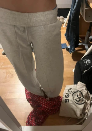 Ljusgrå mjukisbyxor med snörning - Säljer ett par ljusgrå mjukisbyxor med bred resår i midjan och snörning framtill. Byxorna har en relaxed passform och är tillverkade i mjukt bomullsmaterial, perfekta för chill dagar. Fickor på sidorna för extra bekvämlighet.