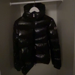 Colmar jacka  - Svart pufferjacka från Colmar med glansig finish och luva. Jackan har en snygg quiltad design, dragkedja framtill och Colmar-logga på ärmen och två fickor där fram,  Nypris: 5000kr, Inga defekter. Säljer billigt för jag vill få den såld för den inte kommer till användning❤️