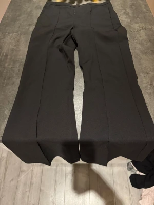 Svarta kostymbyxor från Gina Tricot - Snygga svarta kostymbyxor från Gina Tricot i storlek S. Byxorna har raka ben och en klassisk midja, med pressveck framtill för en clean look. Perfekta att matcha med en cool topp eller hoodie. Materialet är mjukt och har lite stretch.💞💞