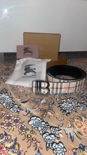 Burberry Reverse Bälte - Säljer ett svär snyggt Burberry reverse bälte. Den går från Beige till svart. Detta har används och är lite slitna vid Hålen som man ska spänna bältet. Bältet är 115cm långt! Om du har några frågor alls är det bara att ställa dom!