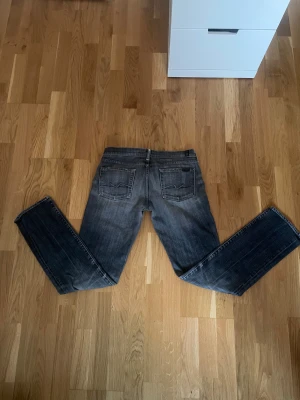 Gråa 7 for all mankind jeans  - Riktigt feta 7 for all mankind jeans med en snygg wash och slitningar. Perfekt för dig som vill utveckla din stil och även rikigt sköna. Rak passform med den klassiska femfickiga designen. 