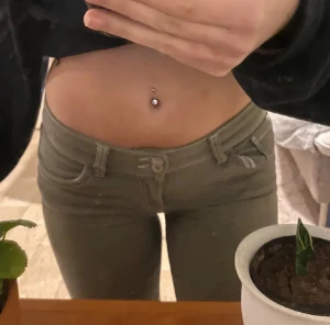 Gröna bootcut byxor med broderade fickor - Snygga gröna bootcut byxor med broderade detaljer på bakfickorna. Byxorna har låg midja, klassisk femficksdesign och stängs med två knappar och dragkedja. Nästan som nya då jag inte användt dem alls mycket ! ❣️