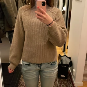 Beige ribbad polotröja stickad - Säljer en beige stickad tröja med ribbad struktur och lång ärm. Tröjan har en hög krage och är i loose passform, perfekt för dig som gillar en chill och enkel stil. Materialet är mjukt och värmande, passar grymt till jeans eller cargo. Tröjan är i bra skick och säljer den pågrund av att ja inte använder den så mycket💕