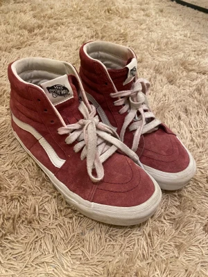 Slutsålda Vans sneakers - Säljer ett par Vans Sk8-Hi sneakers i vinrött mocka med vita detaljer och snörning. Klassisk hög modell med rund tå och platt sula. Insidan har Vans-logga och yttersidan har den ikoniska vita sidoremsan. Skorna är slutsålda och finns inte längre på hemsidan i denna modell, därav priset💓Köpt i storlek 37 men passar även bra i 38🫶🏻
