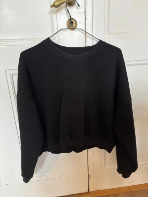 Svart croppad sweatshirt - Svart croppad sweatshirt från 157 med rund hals och ribbade muddar. Tröjan har en loose passform och är tillverkad i mjuk bomullsmix som är perfekt för kyliga dagar. Enkel och stilren design utan mönster eller detaljer, passar dig som gillar basic och oversized. 💞 Jag som är en S kan använda denna då den är rätt liten i storleken! 