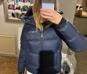 Mörkblå Sail Racing dunjacka - Säljer en mörkblå dunjacka från Sail Racing. Jätte tjock och håller värmen bra. Använd men fortfarande i jätte bra skick. Nypris 4000kr