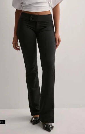 Svarta bootcut byxor med hög midja - Snygga svarta byxor med bootcut-snitt och hög midja. De har två knappar framtill och sitter tajt över höfterna innan de blir vidare nedtill. Perfekta för dig som gillar en stilren och trendig look. Materialet är mjukt och följsamt. För mer frågor är det bara att dma💕