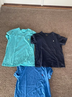 Tre Polo Ralph Lauren t-shirts - Tjena! Säljer tre snygga t-shirts från Polo Ralph Lauren. En är ljusblå med gul logga på bröstfickan, en marinblå med vit logga och en blå med röd logga på bröstfickan. Alla har rund hals och korta ärmar, tillverkade i mjuk bomull. Perfekt för dig som gillar klassisk stil. Skick 8/10. Storlek: small/m. Bara att ställa frågor om det är något. Priset går att diskutera!😊