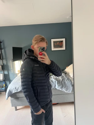 Marinblå dunjacka Peak Performance - Säljer en svart dunjacka från Peak Performance med huva. Jackan har dragkedja framtill, två sidofickor och lång ärm. Perfekt för kalla dagar är i bra skick men är använd rätt så mycket säljer den pga för att den är för liten kan diskutera pris vid snabb affär och fråga vid minsta lilla!