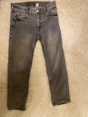 Grå slim fit jeans från H&M, stl 146 - Snygga grå jeans från H&M i slim fit-modell med justerbar midja. Klassisk femficksdesign och raka ben med lätt tvättad look. Perfekt för dig som gillar en stilren och enkel vibe. Passar dig som vill ha bekväma jeans med lite smalare passform.
