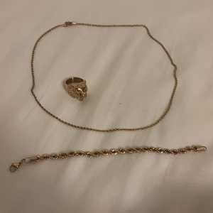 Guld smycken allt för 400kr - Snyggt set med guldpläterad ring med tigerhuvud, tvinnat armband och matchande halsband. Ringen har detaljerat tigeransikte som ger en cool vibe. Armbandet och halsbandet har tvinnad kedja som ger extra stilpoäng. Perfekt för dig som vill sticka ut med dina accessoarer.