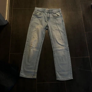 Ljusblå jeans från Lindex, rak modell - Ljusblå jeans från Lindex i rak passform med klassiska fem fickor och gylf med knapp. Jeansen har en enkel, stilren look och är tillverkade i bomull. Perfekta för en avslappnad och trendig stil.