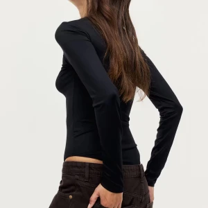 Svart långärmad body - Säljer en svart, tight och långärmad bodysuit från HM. Toppen har rund halsringning och är tillverkad i mjukt, stretchigt syntetmaterial som sitter snyggt mot kroppen. Perfekt att styla med jeans eller kjol för en clean look. Knappt använd💙🩵
