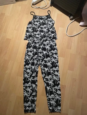 Jumpsuit med mönster av palmträd från H&M. - Svart och vit jumpsuit med mönster av palmträd från H&M i storleken 164.