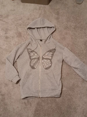 Grå hoodie med fjäril - Snygg grå hoodie med dragkedja och en fjäril framtill🦋